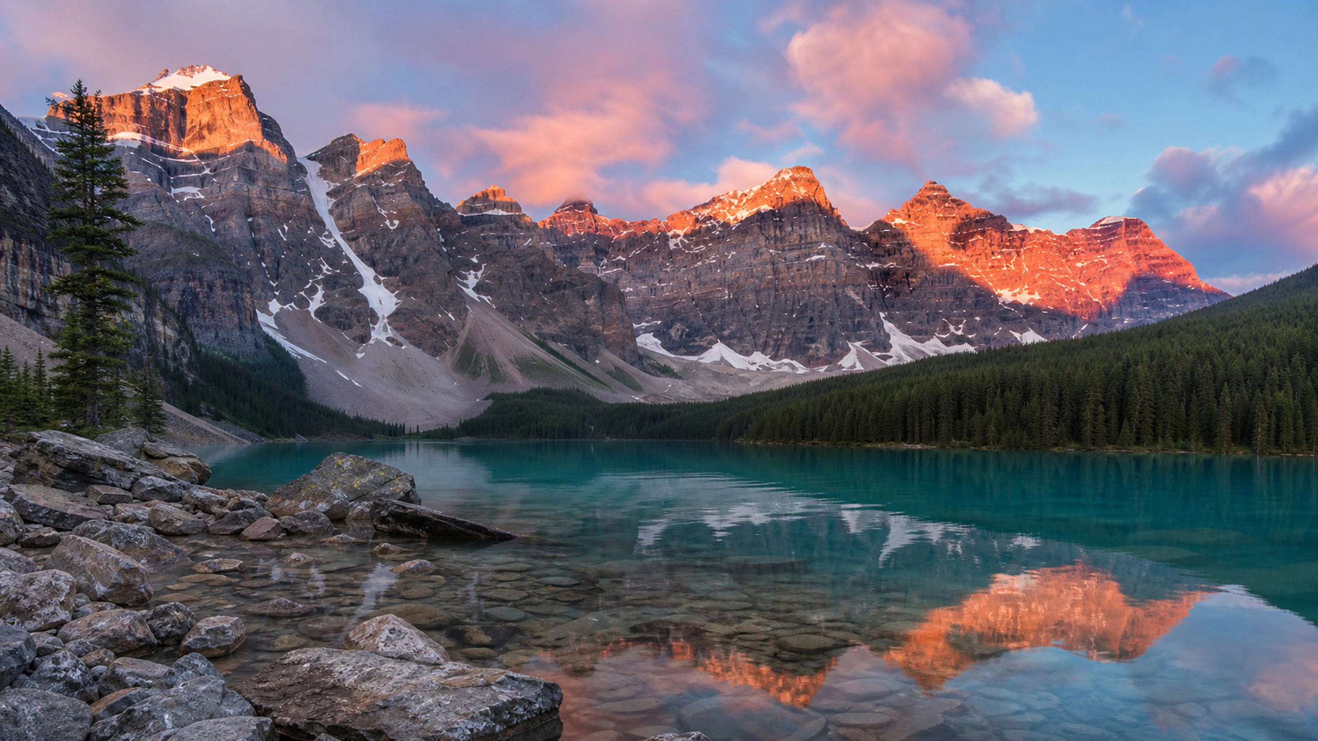 Turquoise moraine lake beneath jagged peaks, first pink light, low shoreline viewpoint, original 4K nature wallpaper