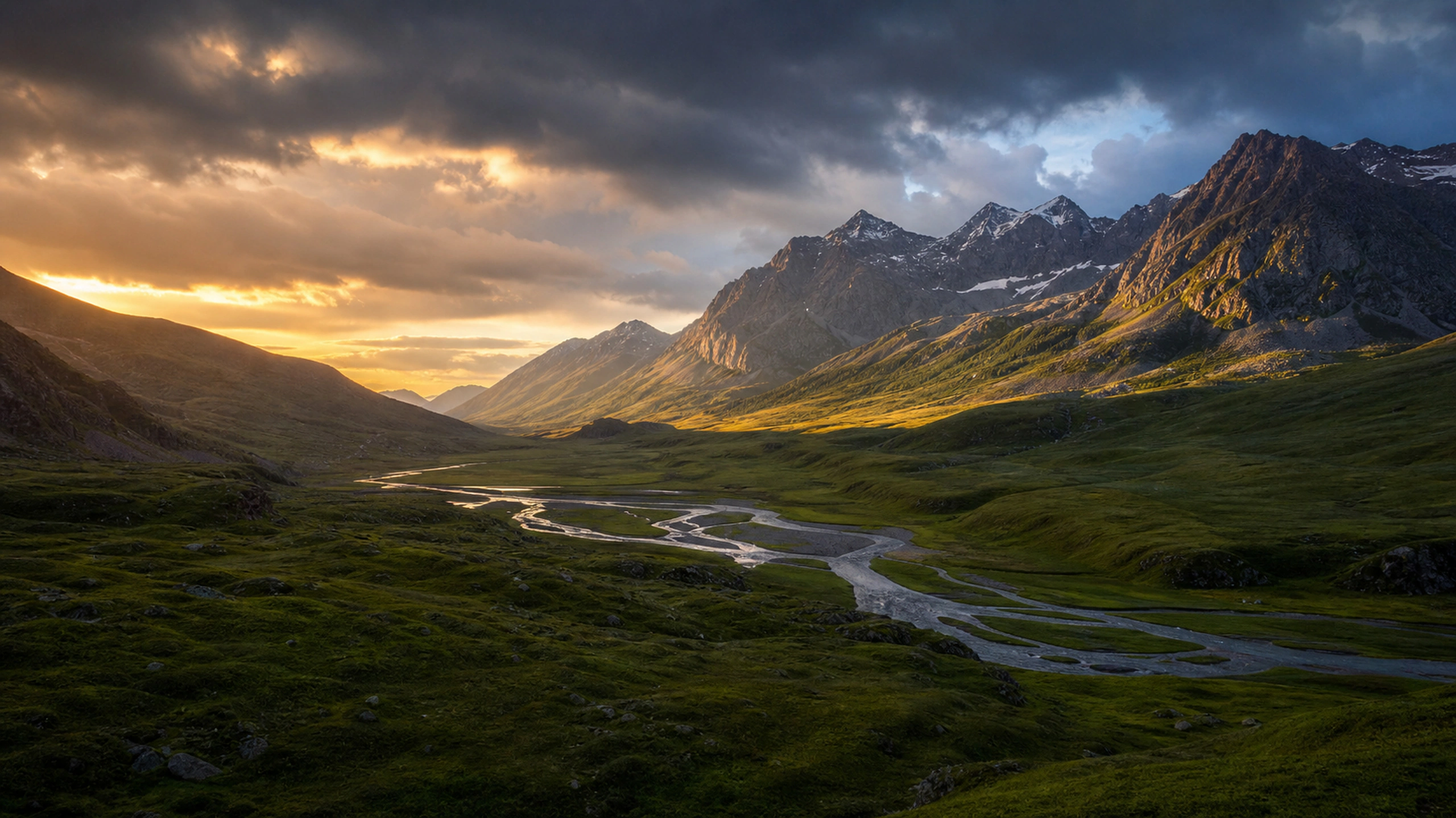 Wide green alpine valley with braided stream, warm light entering beneath storm clouds, original 4K nature wallpaper