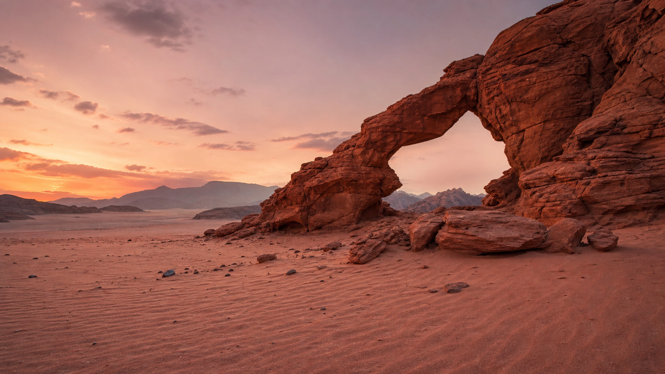 Natural stone arch above rippled sand during a restrained rose-colored sunset, original 4K desert wallpaper