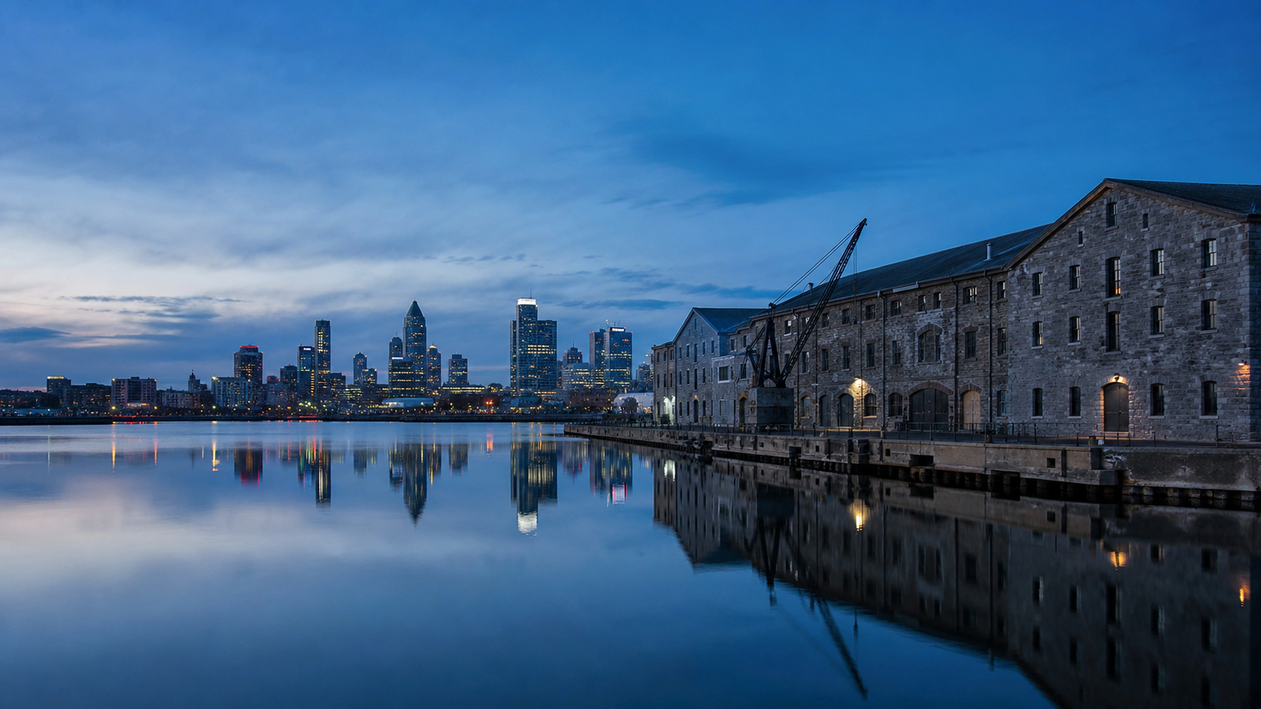 Weathered stone warehouses beside modern distant towers at tranquil blue hour, original 4K cities wallpaper