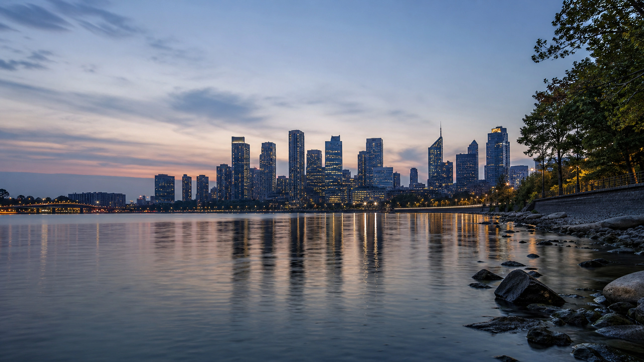 Low riverside view toward an original skyline, soft dusk lamps and long reflections, original 4K cities wallpaper