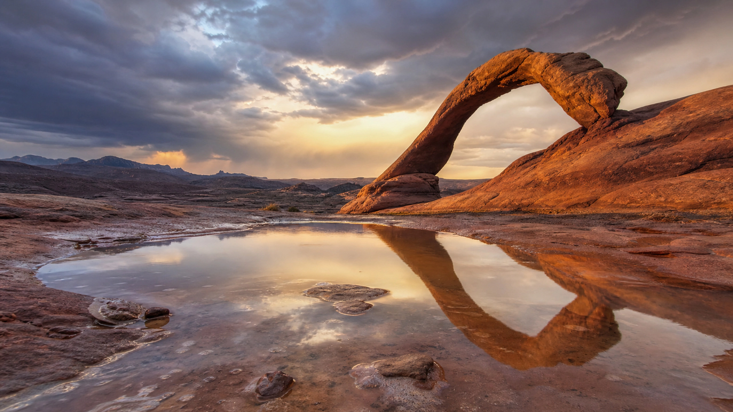 Isolated desert arch reflected in a temporary rain pool after a storm, original 4K desert wallpaper