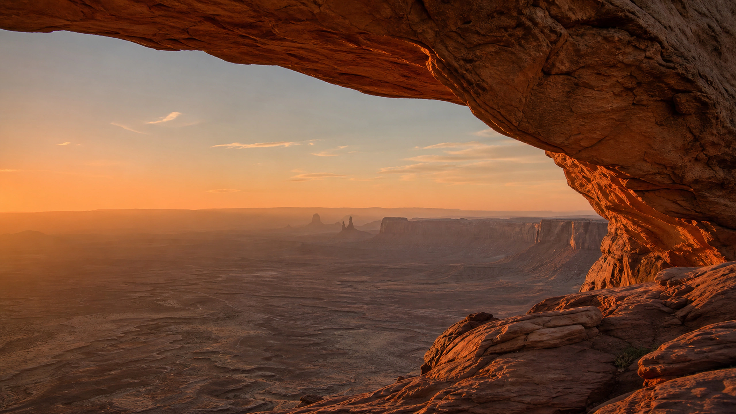 Delicate sandstone window above a rugged desert plateau, restrained orange afterglow, original 4K desert wallpaper