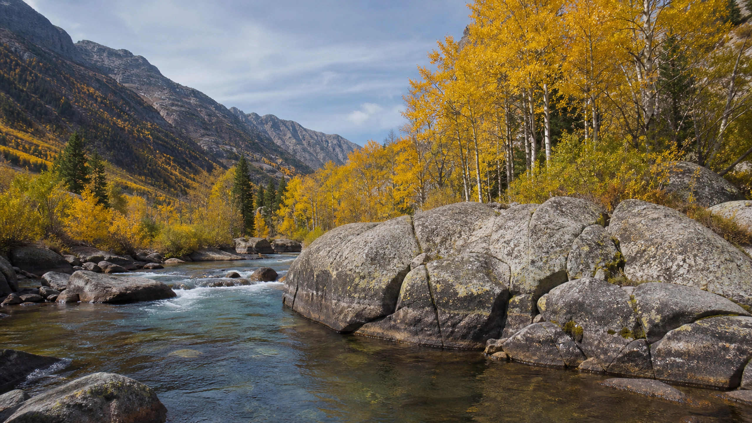 Clear autumn river bending around immense granite boulders beneath yellow aspens, original 4K lakes rivers wallpaper