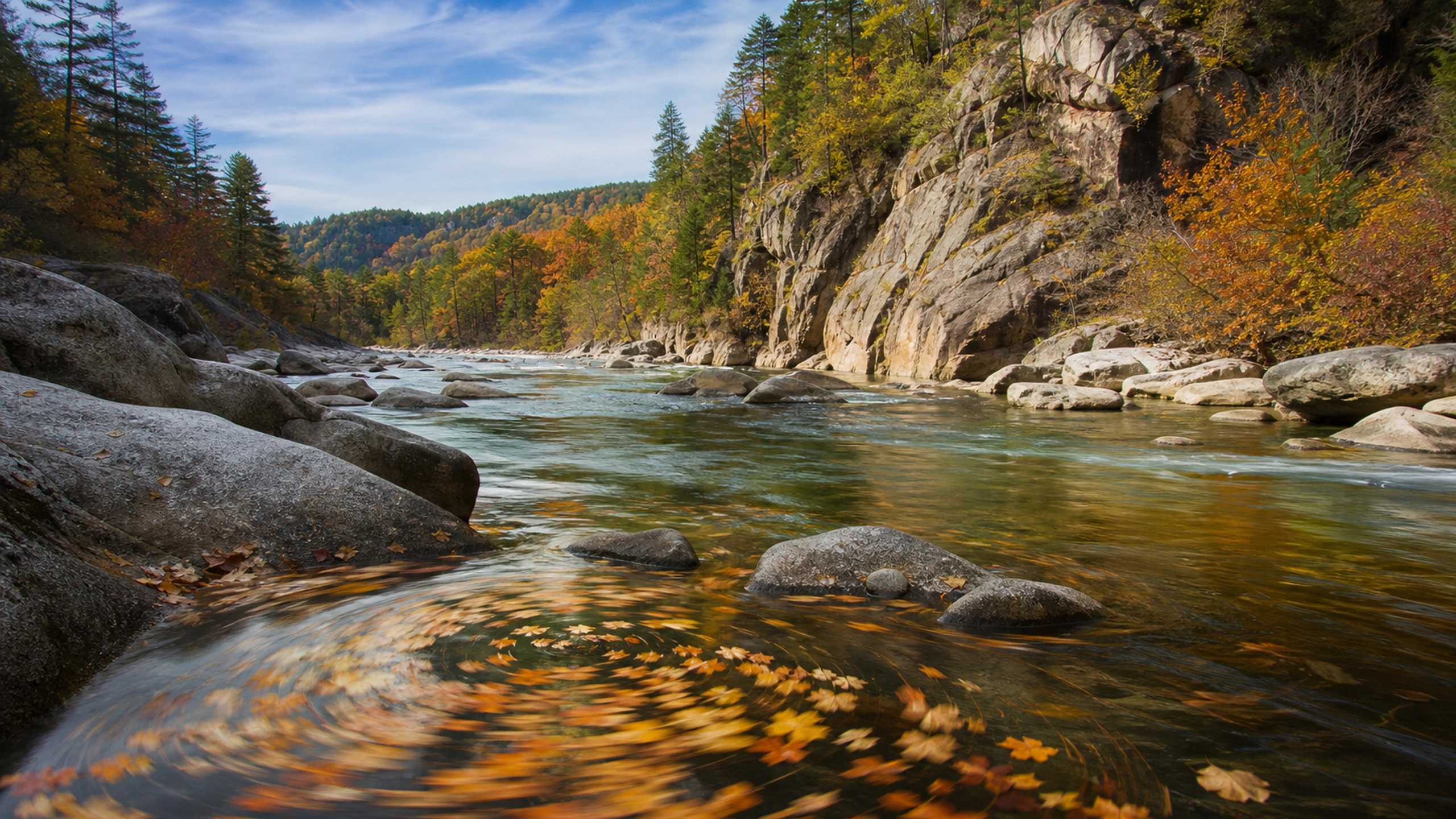 Foreground eddy carrying scattered autumn leaves with a wide granite river beyond, original 4K lakes rivers wallpaper