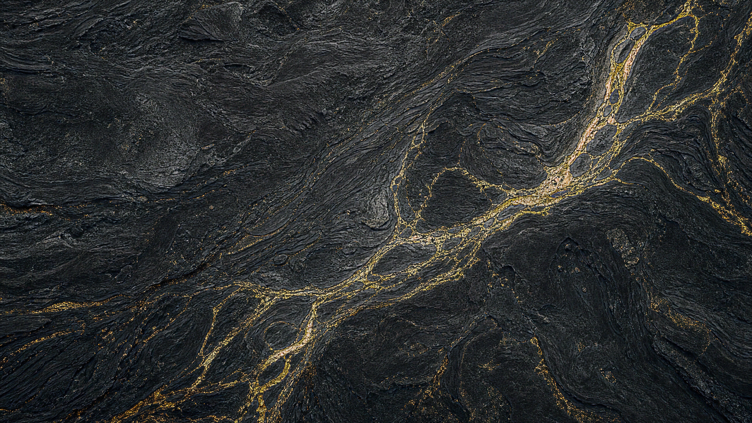 Top-down abstract terrain of charcoal ridges divided by branching gold fault lines, fine contour texture and believable mineral depth, original 4K dark amoled wallpaper