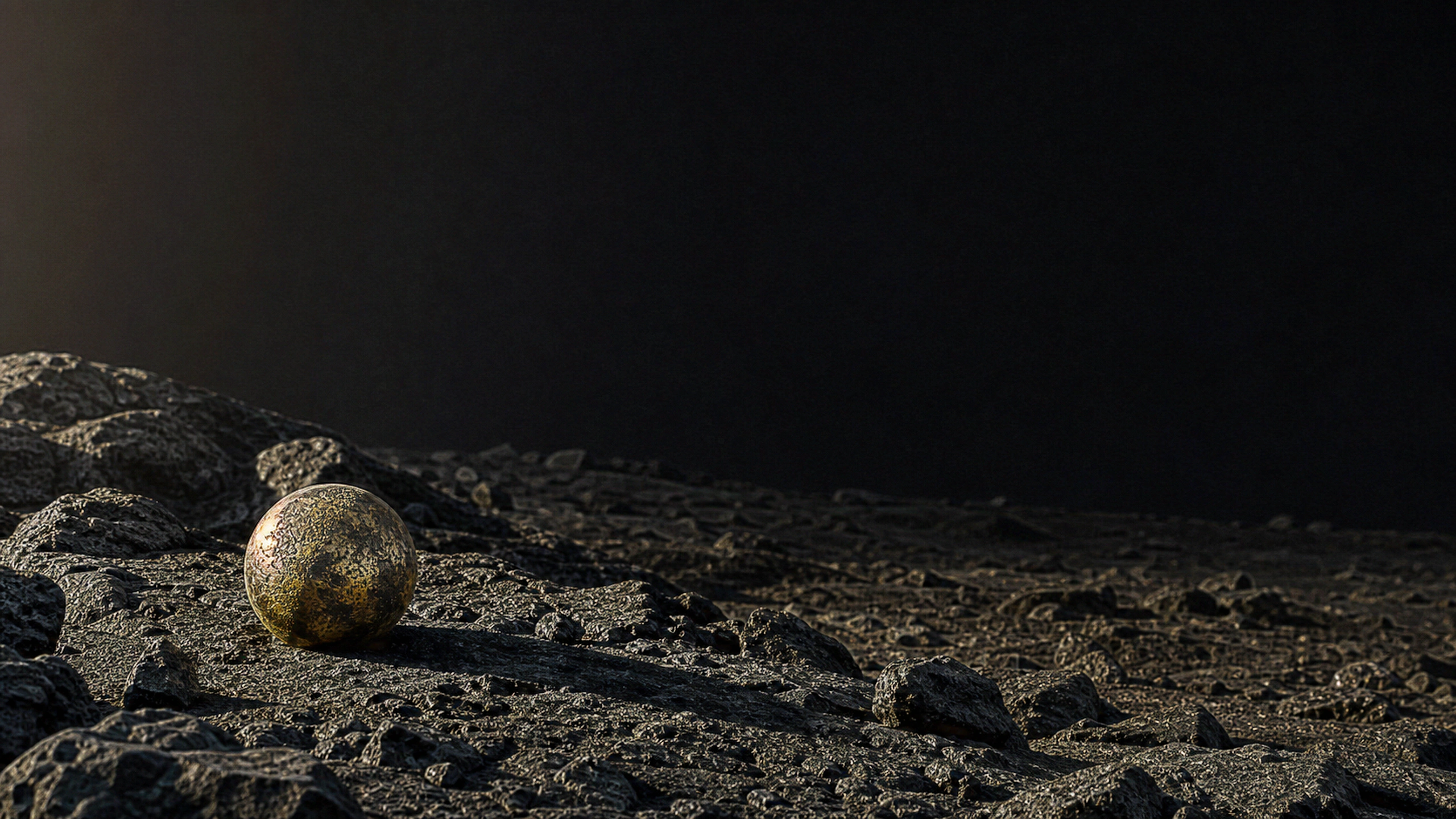 Single weathered brass sphere resting among jagged matte-black stones, tactile oxidation, granular basalt and a long asymmetric shadow, original 4K dark amoled wallpaper