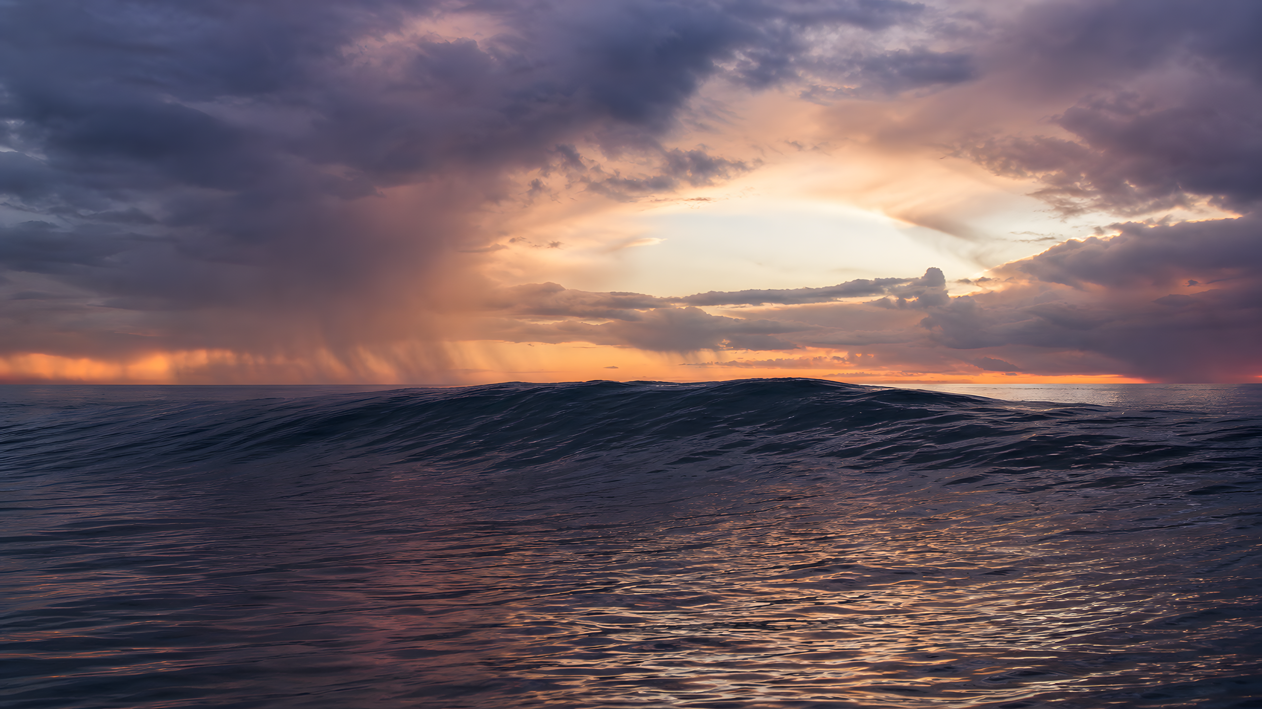 One quiet luminous ocean swell rising beneath a violet and copper sky as distant rain retreats at sunset, original 4K ocean wallpaper