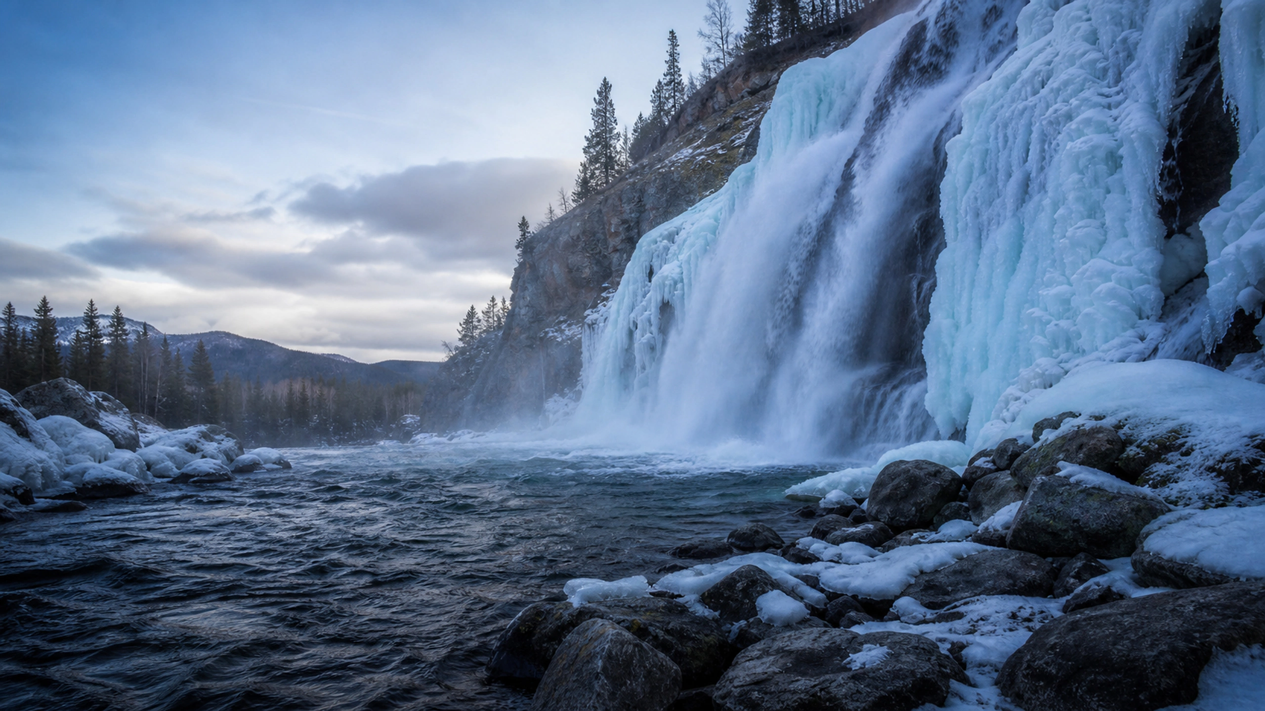 Partially frozen winter waterfall with moving dark water beneath blue-white ice, original 4K lakes rivers wallpaper
