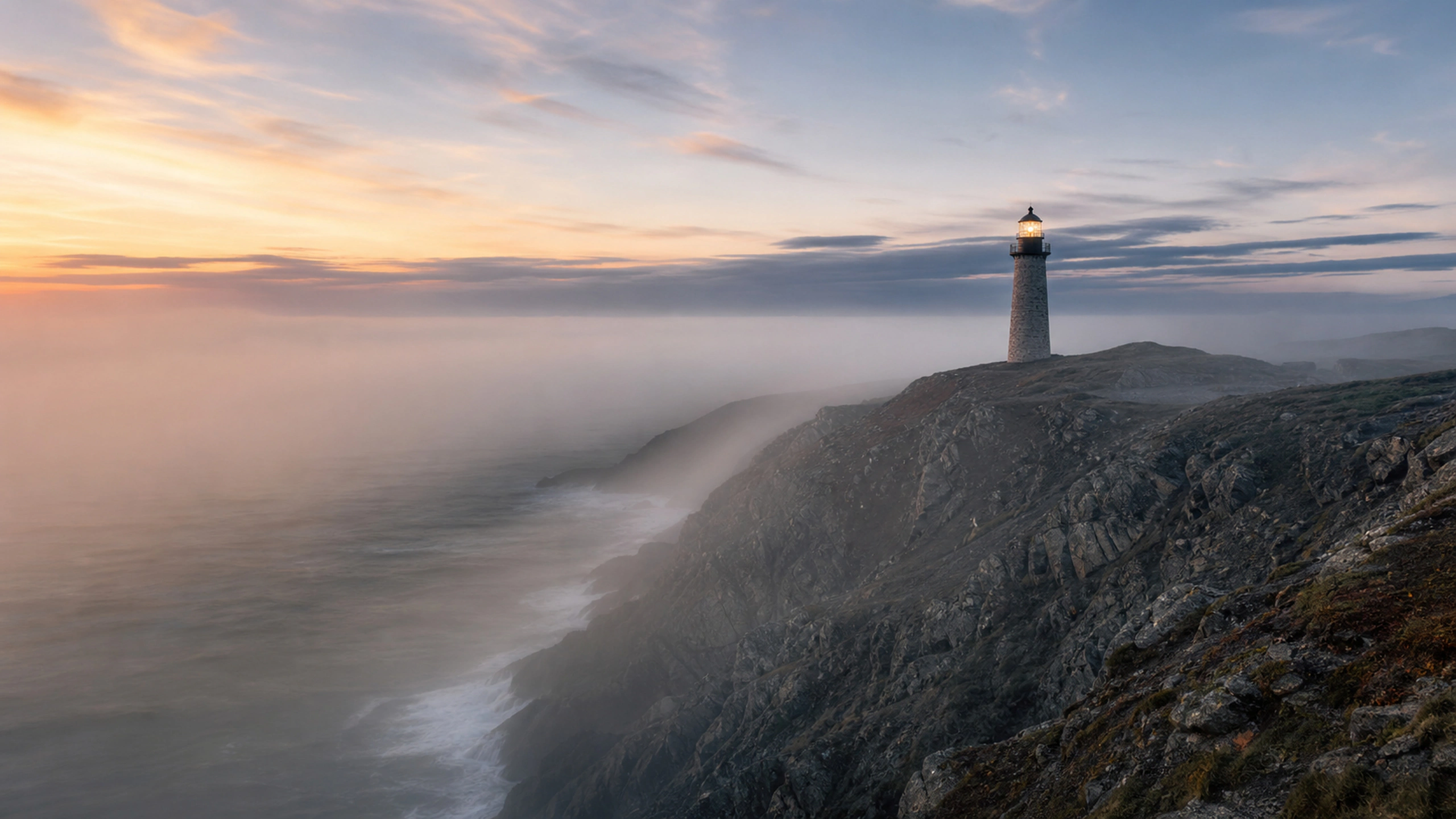 Lighthouse tower emerging from dense sea fog with a restrained warm lamp, original 4K landmarks wallpaper