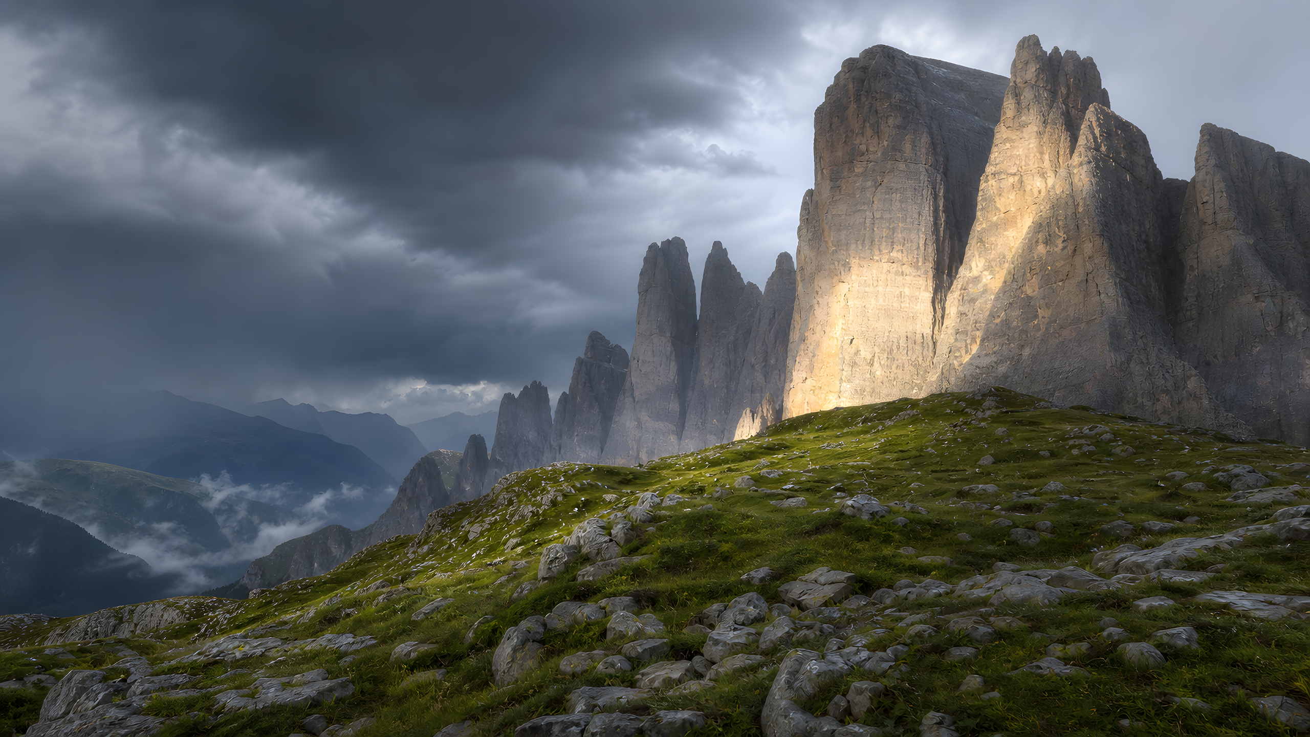 Pale limestone spires rising from a high grassy saddle after a summer thunderstorm, with one rain-wet wall caught by late sunlight above a misty valley, original 4K mountains wallpaper