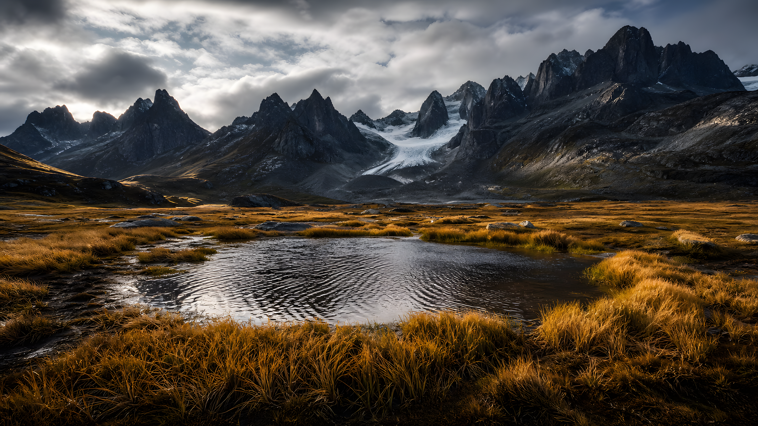 Jagged late-autumn tooth peaks and a small pale glacier beyond wind-bent amber tussock and a rippled rain pool beneath fast broken cloud, original 4K mountains wallpaper