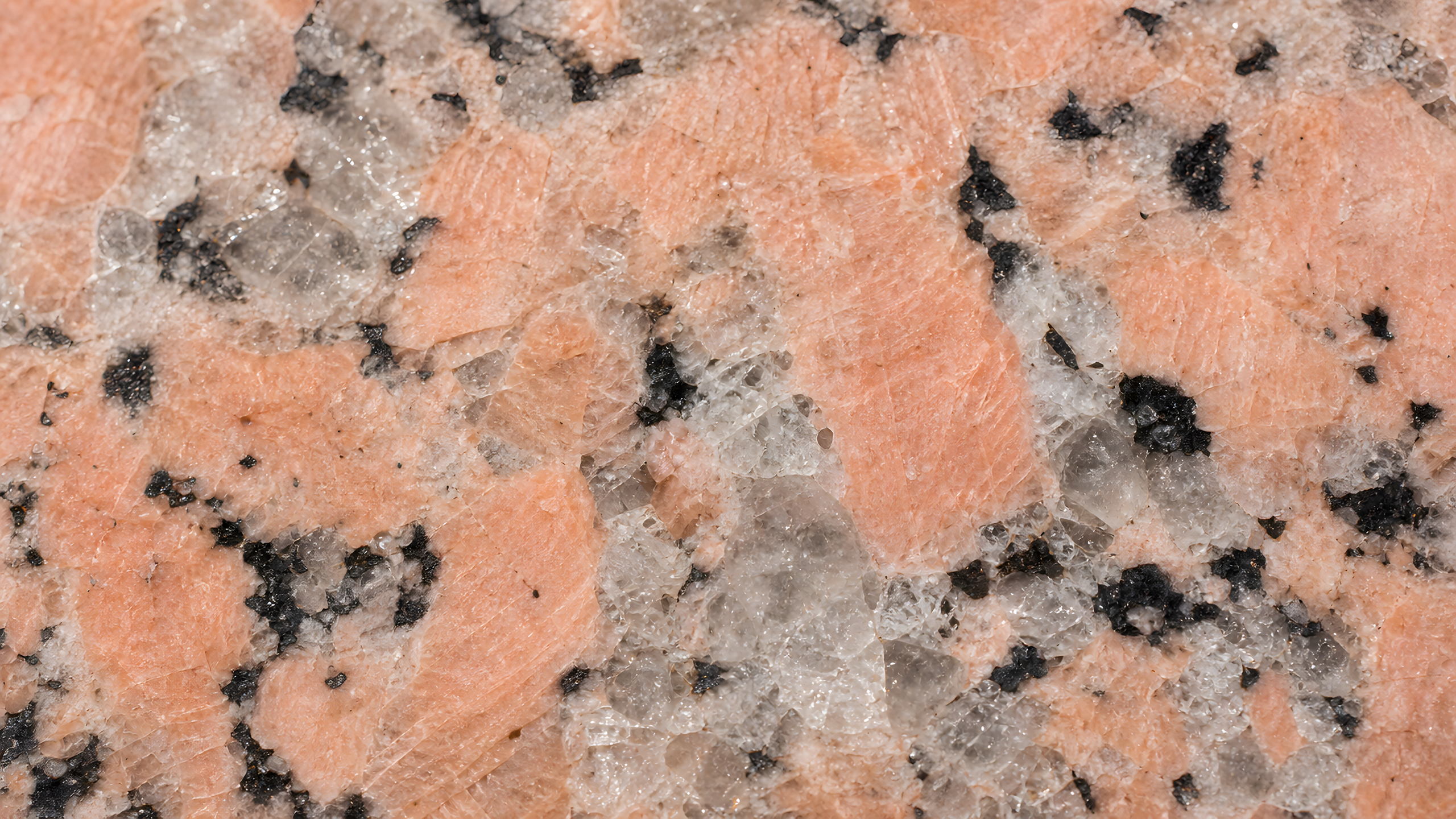 Pink granite macro texture with salmon feldspar, clear quartz, and black mica grains in original 4K