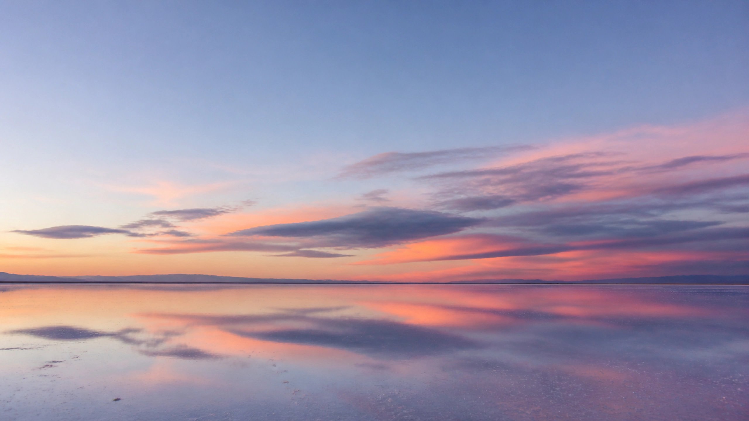 Shallow reflective plain beneath soft receding gray and coral cloud, original 4K pastel wallpaper