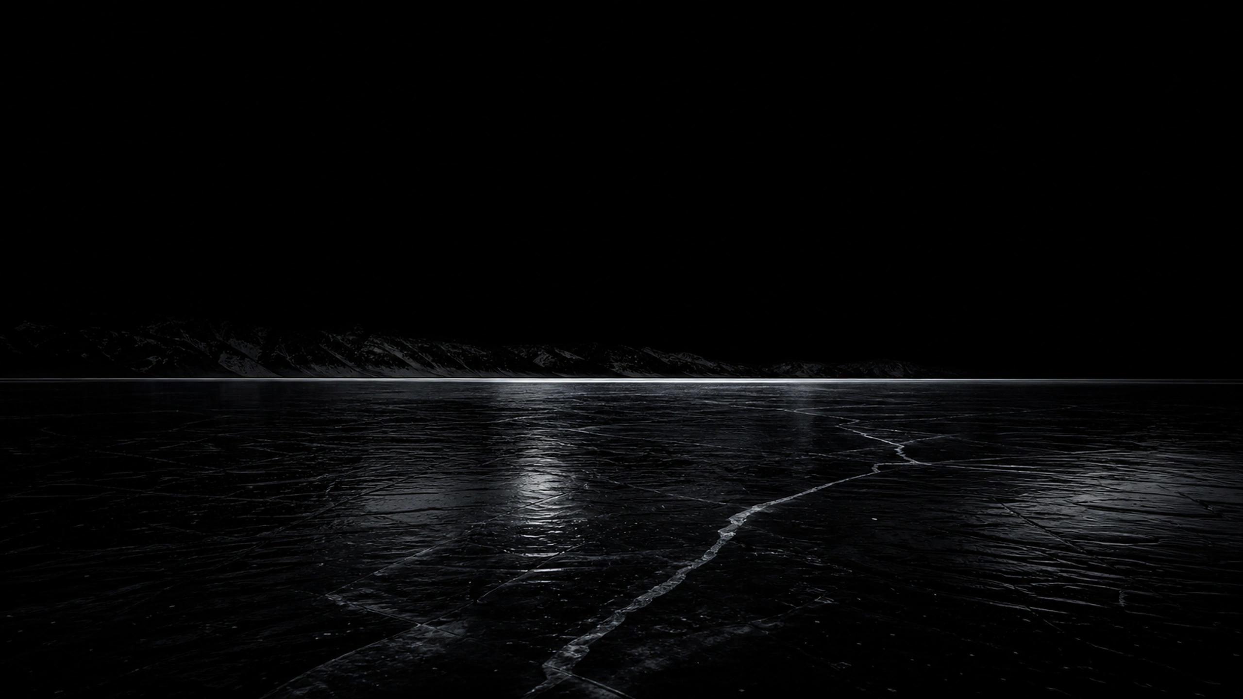 Wide frozen lake of near-black clear ice reflecting a barely visible mountain ridge, one restrained horizontal glow, original 4K dark amoled wallpaper