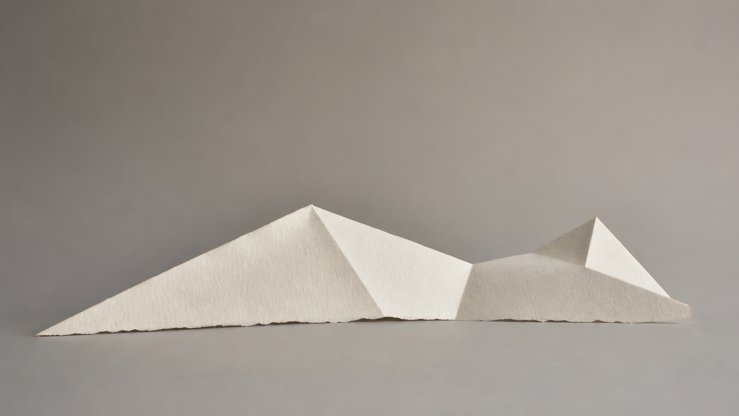 An original hand-folded cotton-paper landscape of three unequal planes forming an asymmetric ridge across a plain warm-gray surface, original 4K minimal wallpaper