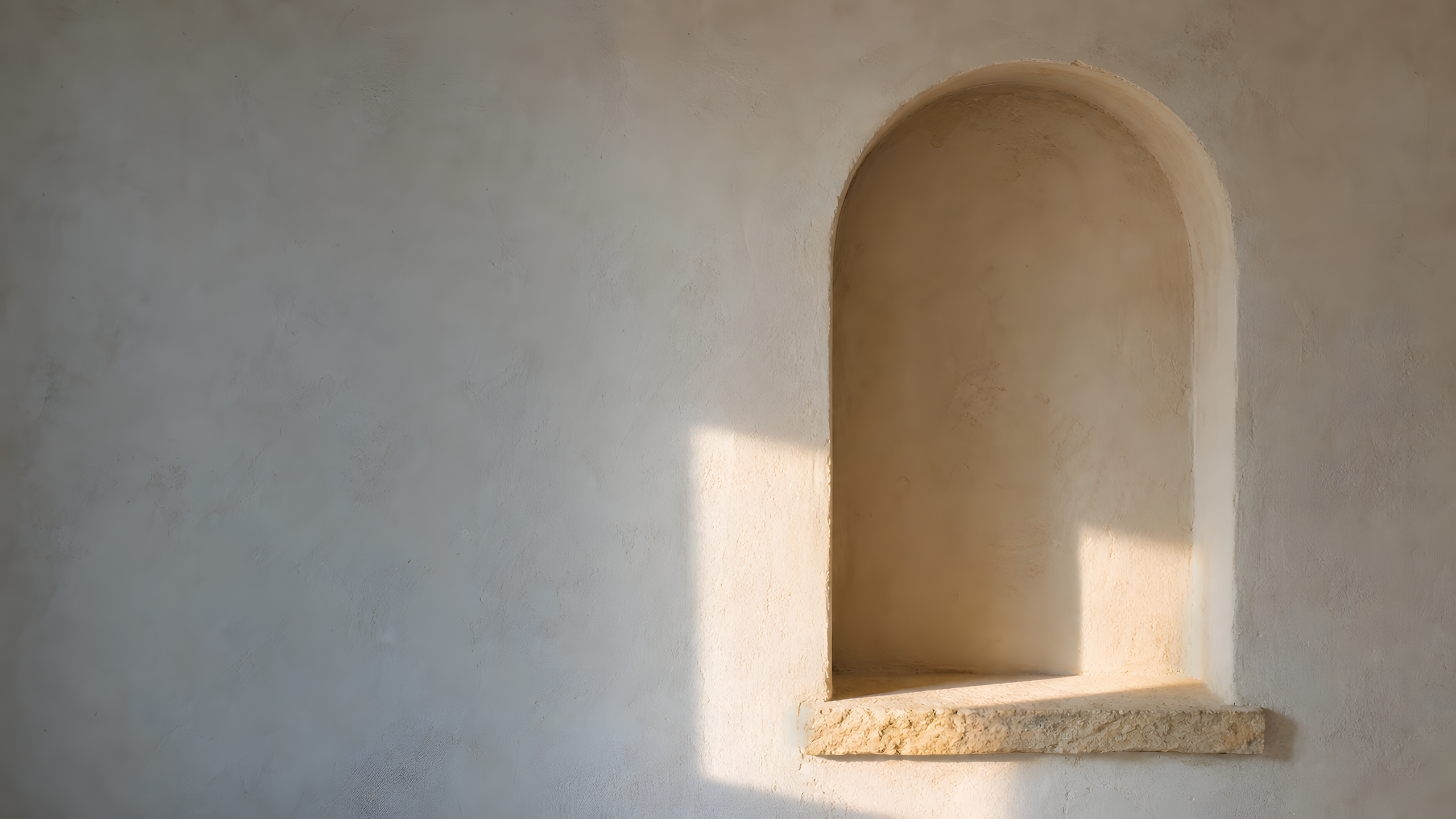 A shallow asymmetrical plaster alcove and low stone ledge crossed by one rectangular winter-afternoon sun patch in an otherwise empty wall, original 4K minimal wallpaper