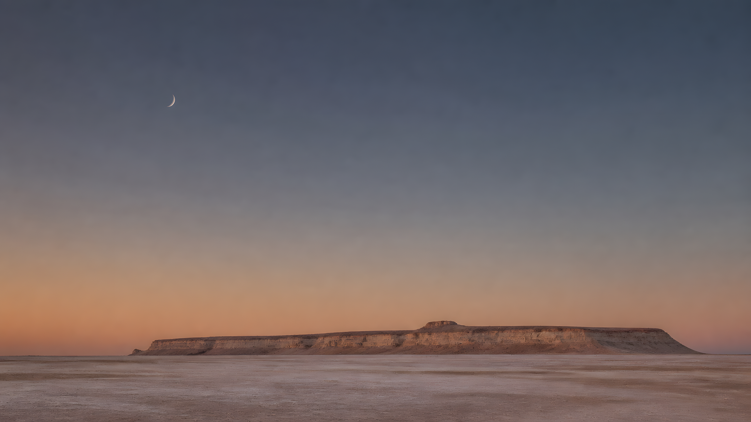 A single distant low sandstone mesa occupying a thin band across an empty pale desert basin beneath muted dusk and a tiny crescent moon, original 4K minimal wallpaper