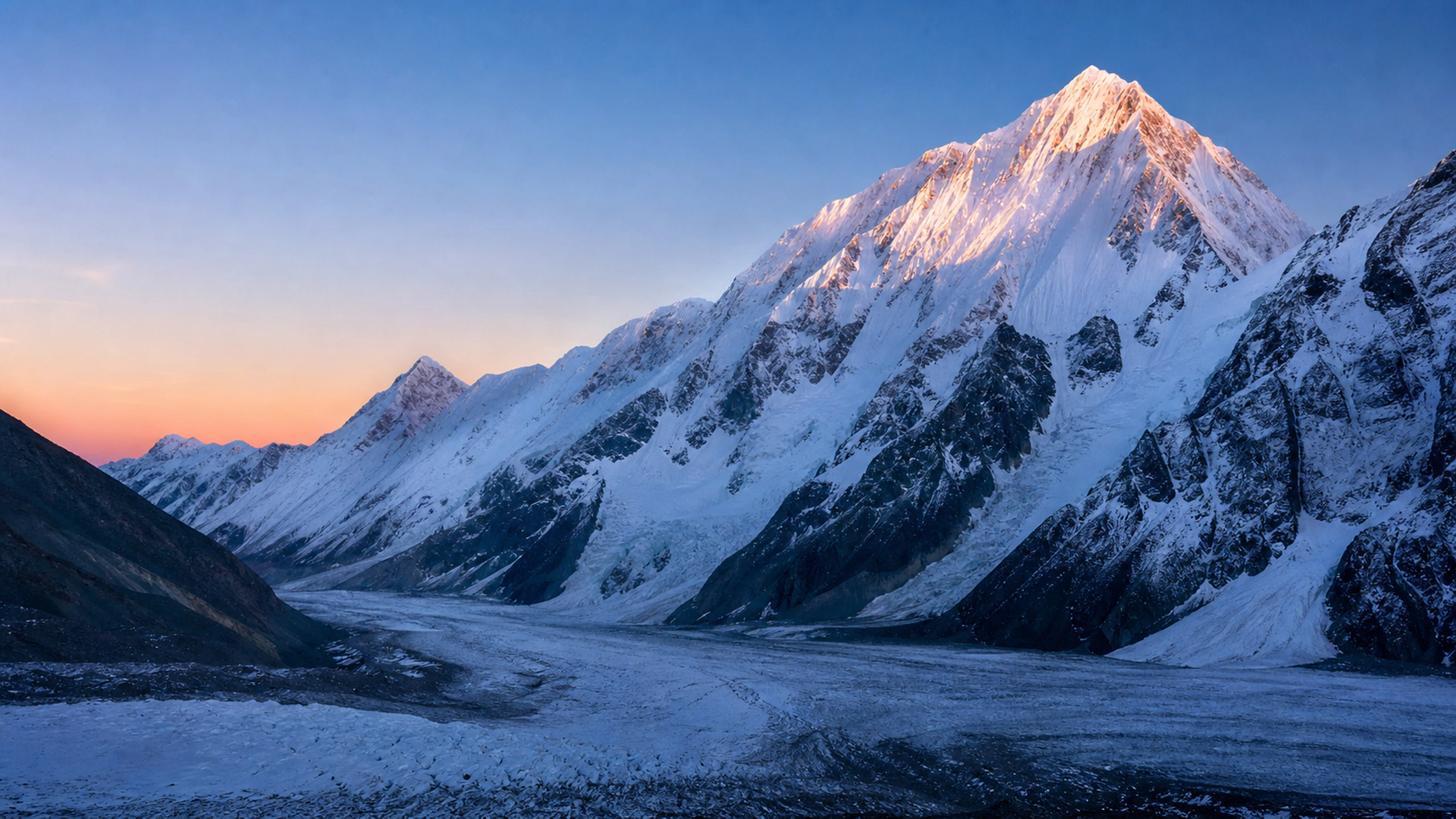 Wide glacier basin beneath towering white peaks and deep blue shadow, original 4K mountains wallpaper