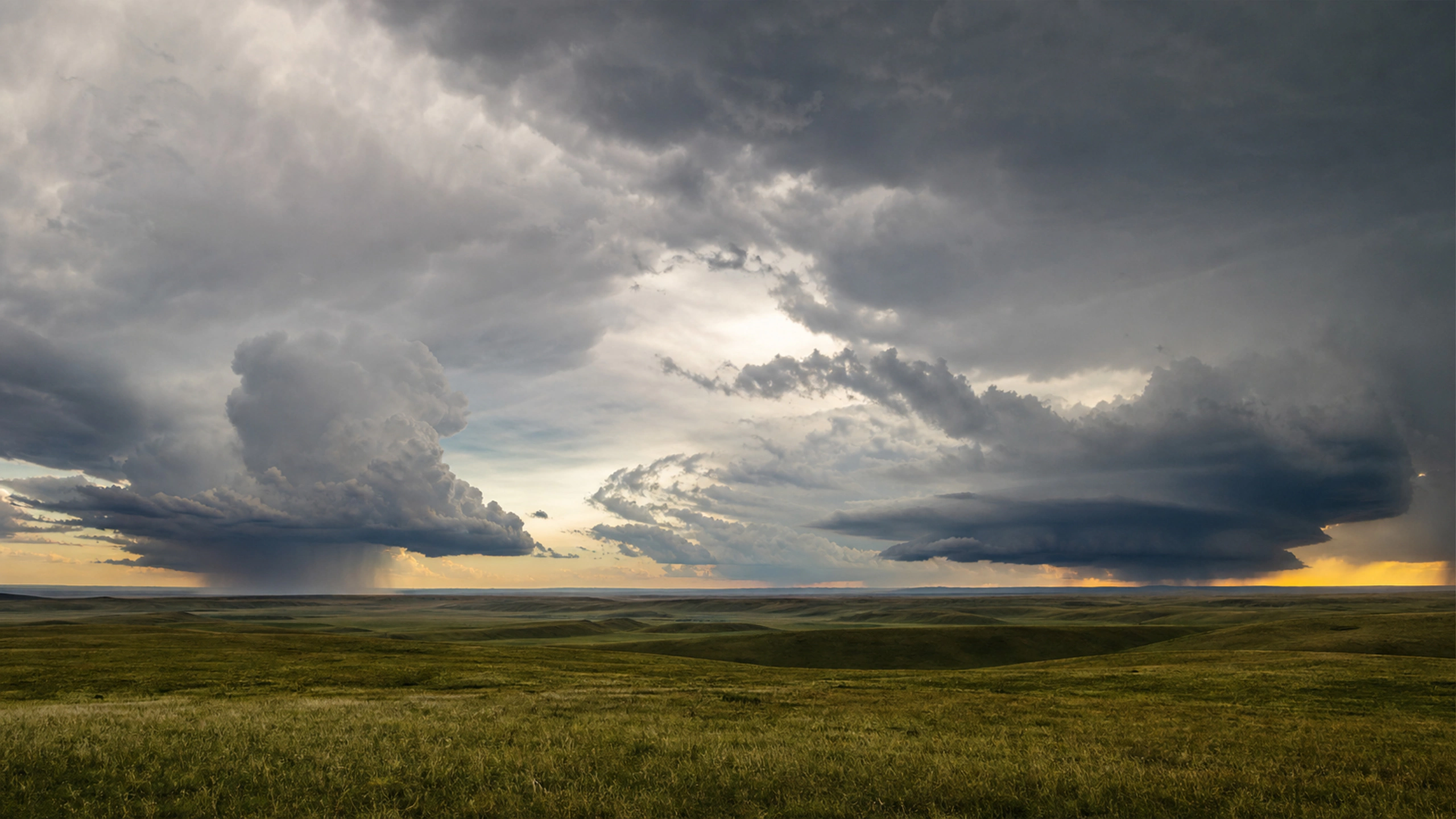 Two separate mature storm cells across wide rolling grassland, original 4K weather wallpaper