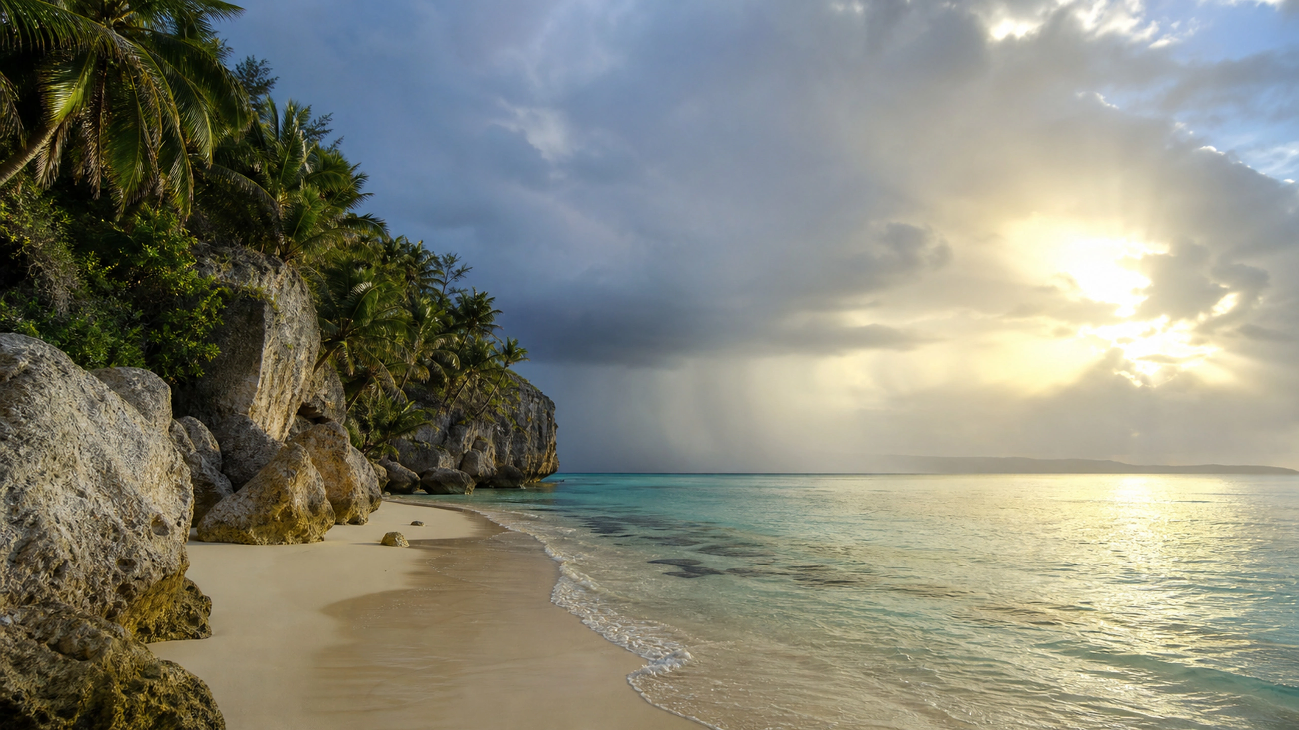 Tropical shore beneath a departing rain squall with sun returning across the sea, original 4K beaches wallpaper