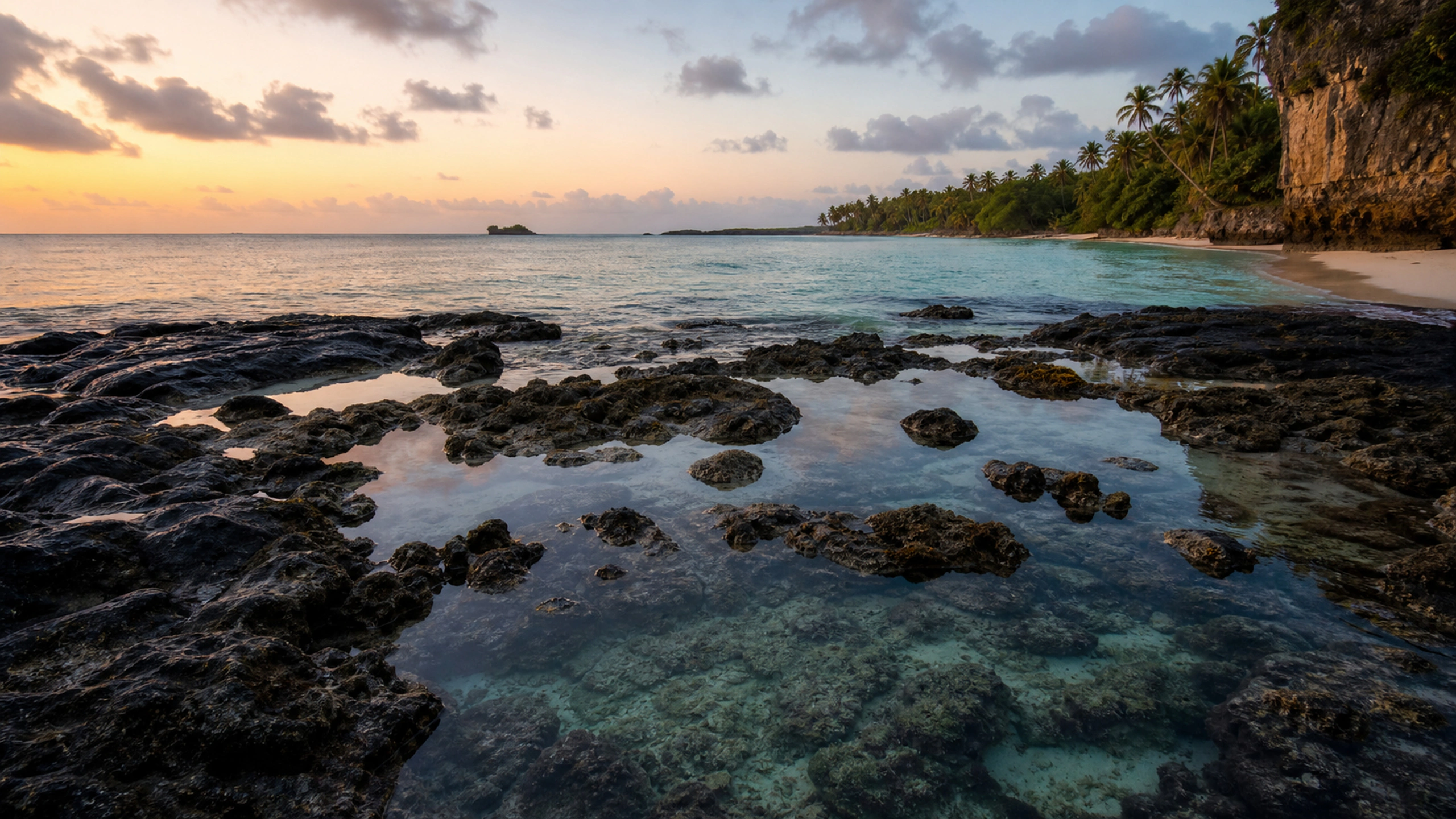 Clear coastal tide pools among dark rock beside a tropical bay, original 4K beaches wallpaper
